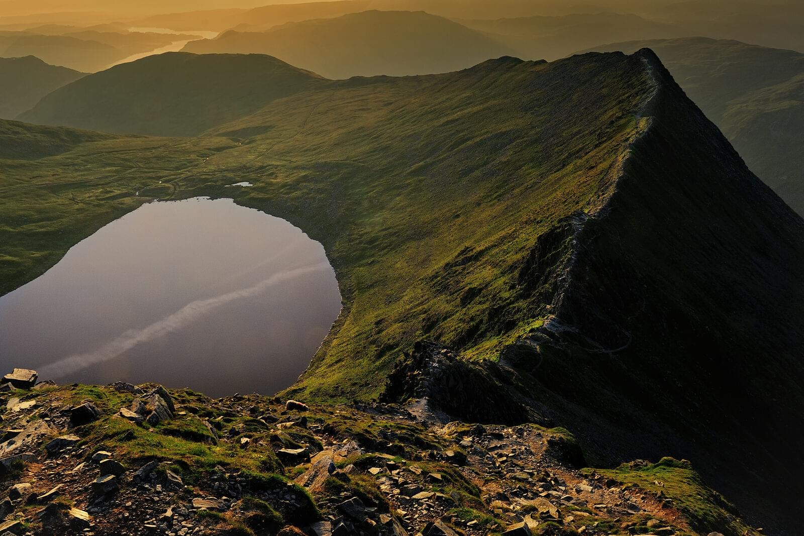 Striding Edge at sunrise: a rocky ridge climbing towards Helvellyn, with Red Tarn in the corrie below
